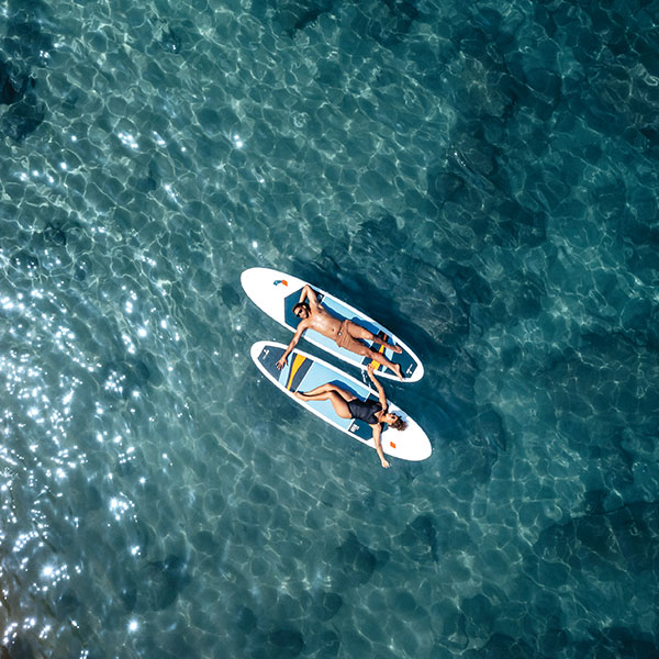 Couple resting on paddle surf boards in crystal clear waters