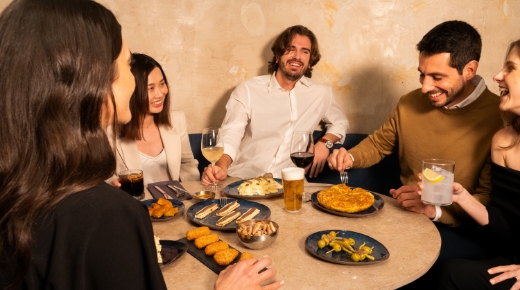 Group of five people sitting at a table enjoying a meal at a restaurant