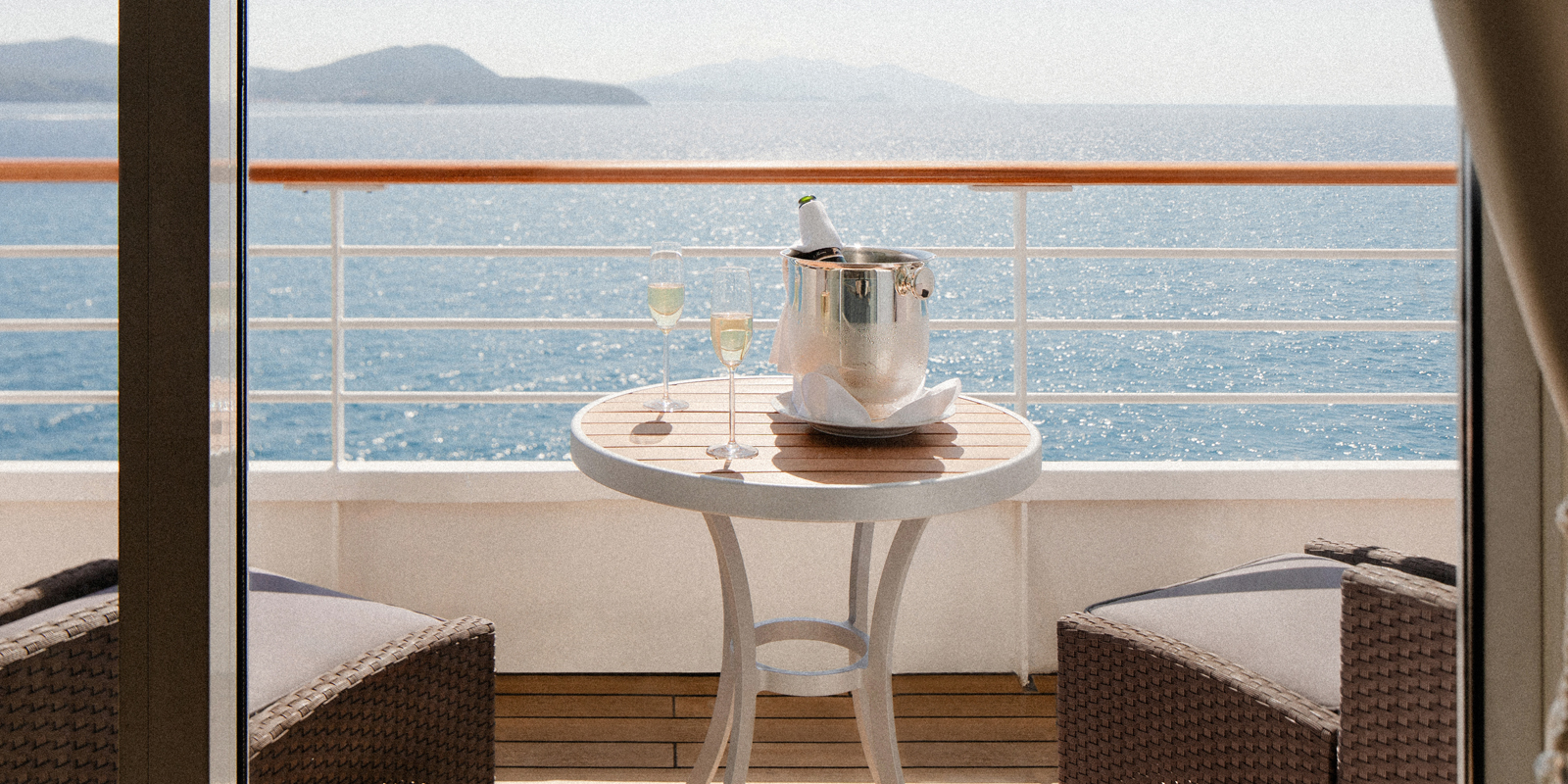 Bottle of champagne with glasses sitting on the balcony of ships cabin
